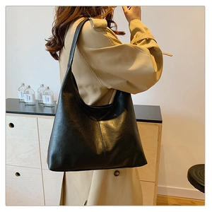 Vista dettagliata della borsa tote in pelle nera indossata con un trench beige elegante