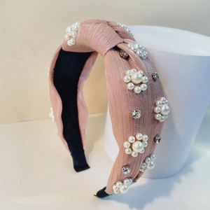 Detail eines rosa Knotenstirnbands mit eleganten Perlblumen und glitzernden Strasssteinen