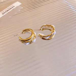 Detail of gold C-shaped hoop earrings wrapped in white velvet chain with handmade tag