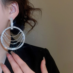 Détail de boucles d'oreilles rondes à pompons avec chaînes en cristal sur le mannequin