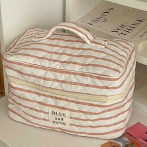 Detail of striped quilted makeup bag with soft texture and sturdy top handle