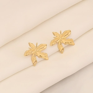 Detailaufnahme der goldenen Sonnenblumen-Ohrstecker auf weichem Stoffhintergrund