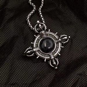 Detail of vintage vajra pendant with blue sandstone inlay on black background