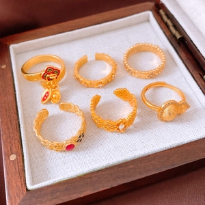 Macro detail of six gold Chinese style rings with ingots and charms in a wooden jewelry box