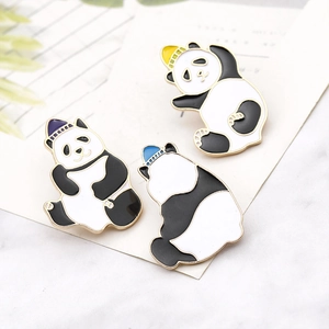 Detailed view of three cute panda enamel pins with colorful hats on marble surface