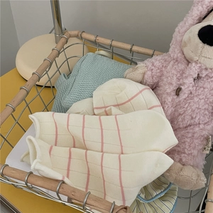 Detail of soft Morandi style striped socks and waffle fabric in a minimalist wire basket