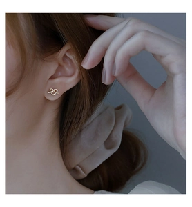 Close-up of heart-shaped intertwined earrings with sparkling cubic zirconia on model
