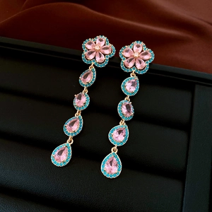 Detailed shot of long tassel earrings with pink stones and blue beads on black leather