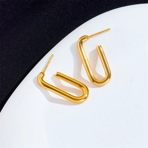 U-shaped gold titanium steel earrings with a polished finish on a white ceramic plate