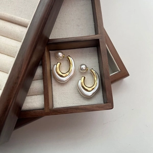 Elegant C-shaped double-layer hoop earrings with white pearls in a wooden jewelry box