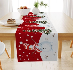 Detail of linen Christmas table runner featuring snowman and tree patterns on wood table