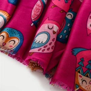 Close-up of cotton linen scarf with colorful cartoon owl patterns and frayed edge