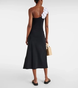 Detail of elegant black one-shoulder dress featuring white 3D floral accents on back strap