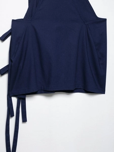 Detailed close-up of dark blue linen fabric texture and fine stitching on a sarong skirt