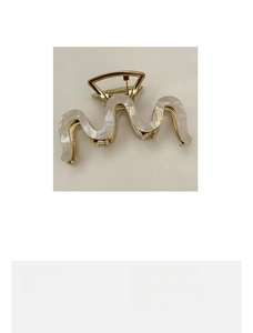 Detailed view of an 8.5cm gold wave-shaped hair claw with white marble acetate inlay