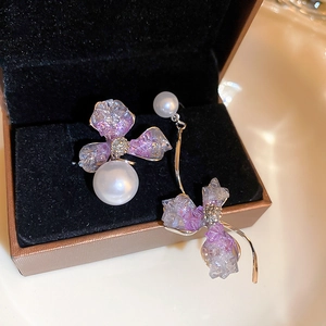 Macro detail of asymmetric lilac crystal flower earrings with large pearl accents