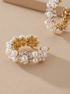 Close-up of C-shaped gold hoops with clustered pearls and sparkling crystals in baroque style