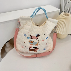 Close-up of quilted off-white bag with cute cartoon dachshund embroidery and blue handles