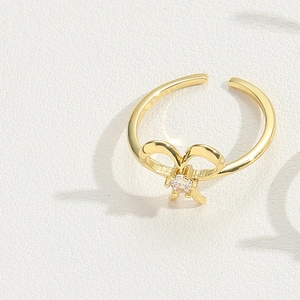 Macro shot of gold bow-shaped open ring featuring a sparkling central round gemstone