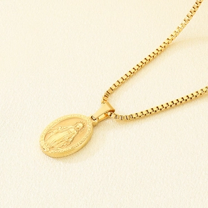 Close-up of golden box chain and oval Virgin Mary religious pendant with detailed engraving