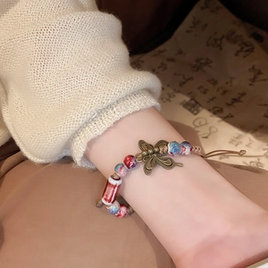 Close-up of vintage butterfly charm and blue-red ceramic beads on woven bracelet