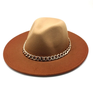 Detail of fedora hat with khaki crown, red brim, and chunky gold chain decoration