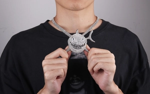 Close-up of a silver shark pendant with shimmering rhinestones on a thick Cuban chain