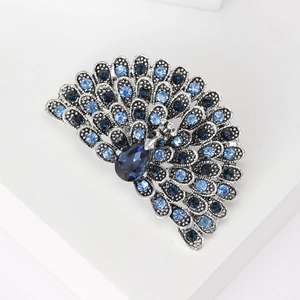 Detailed view of silver peacock brooch with sparkling blue rhinestones and crystal feathers