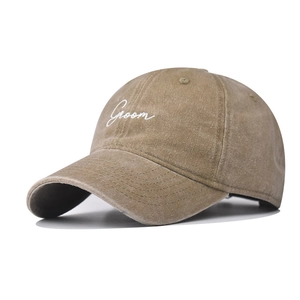 Macro detail of 'Groom' white cursive embroidery on washed khaki cotton canvas baseball cap