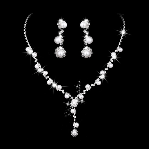 Detailed close-up of bridal necklace and earring set with pearls and rhinestones on black background