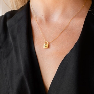 Model wearing a gold padlock necklace with a letter C engraved on the pendant