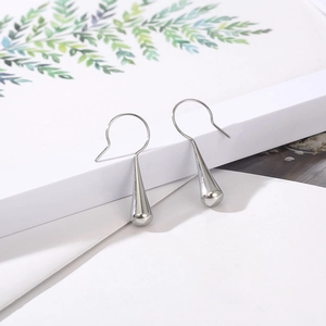 Polished silver teardrop earrings with a sleek minimalist hook design on white geometric stand