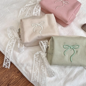 Detailed top view of pastel cotton makeup bags with bow embroidery and lace ribbons