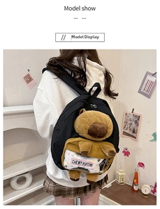Close-up of black backpack featuring a 3D plush capybara and a transparent front pocket