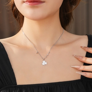 Detail of silver clover pendant necklace with beaded edges worn on woman neck