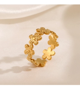 Macro detail of golden five-petal flower ring with matte texture and embossed center dots