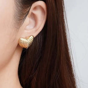 Boucles d'oreilles cœur dorées avec texture nervurée et zircons sur un mannequin