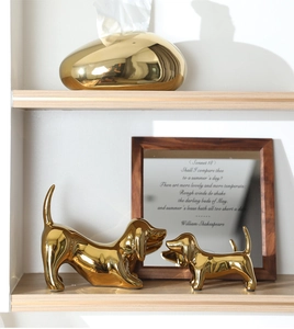 Close-up of golden ceramic dachshund statues and pebble-shaped tissue box with mirror finish