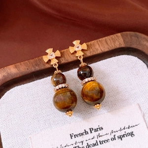 Close-up of vintage tiger eye gourd earrings with gold star and zircon details