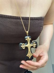 Detail of a large gothic black resin cross pendant with ornate gold fleur-de-lis metal patterns