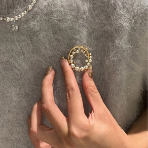 24k gold-plated circular pearl brooch with sparkling zircon on a grey sweater background