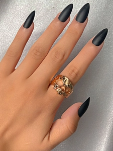 Dettaglio di un anello teschio dorato sulla mano con estetica vintage punk e gotica