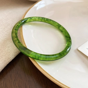 Detailed macro view of translucent green resin bangle with unique marble texture and cloud pattern
