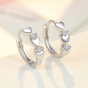 Macro view of silver heart earrings with sparkling cubic zirconia on a white background