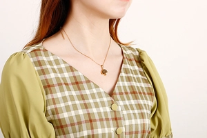 Close-up of a gold tree of life pendant necklace worn by a model on white background