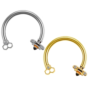 Close-up of gold and silver horseshoe rings featuring bee and honeycomb charms with crystals