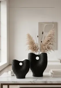 Détail de vases en céramique noir mat avec texture alvéolée et design évidé circulaire