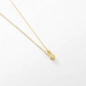 Detailed macro of gold heart lock pendant with sparkling gemstone on a thin chain