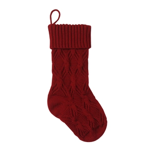 Close-up of red knitted Christmas stocking with diamond pattern and hanging loop on white backdrop