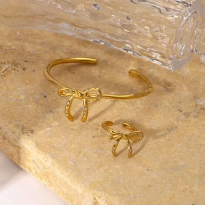 Elegant gold bow jewelry set with diamonds featuring an open bracelet and ring